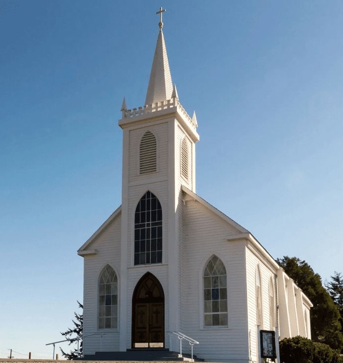 A white church with a steeple and a large window.